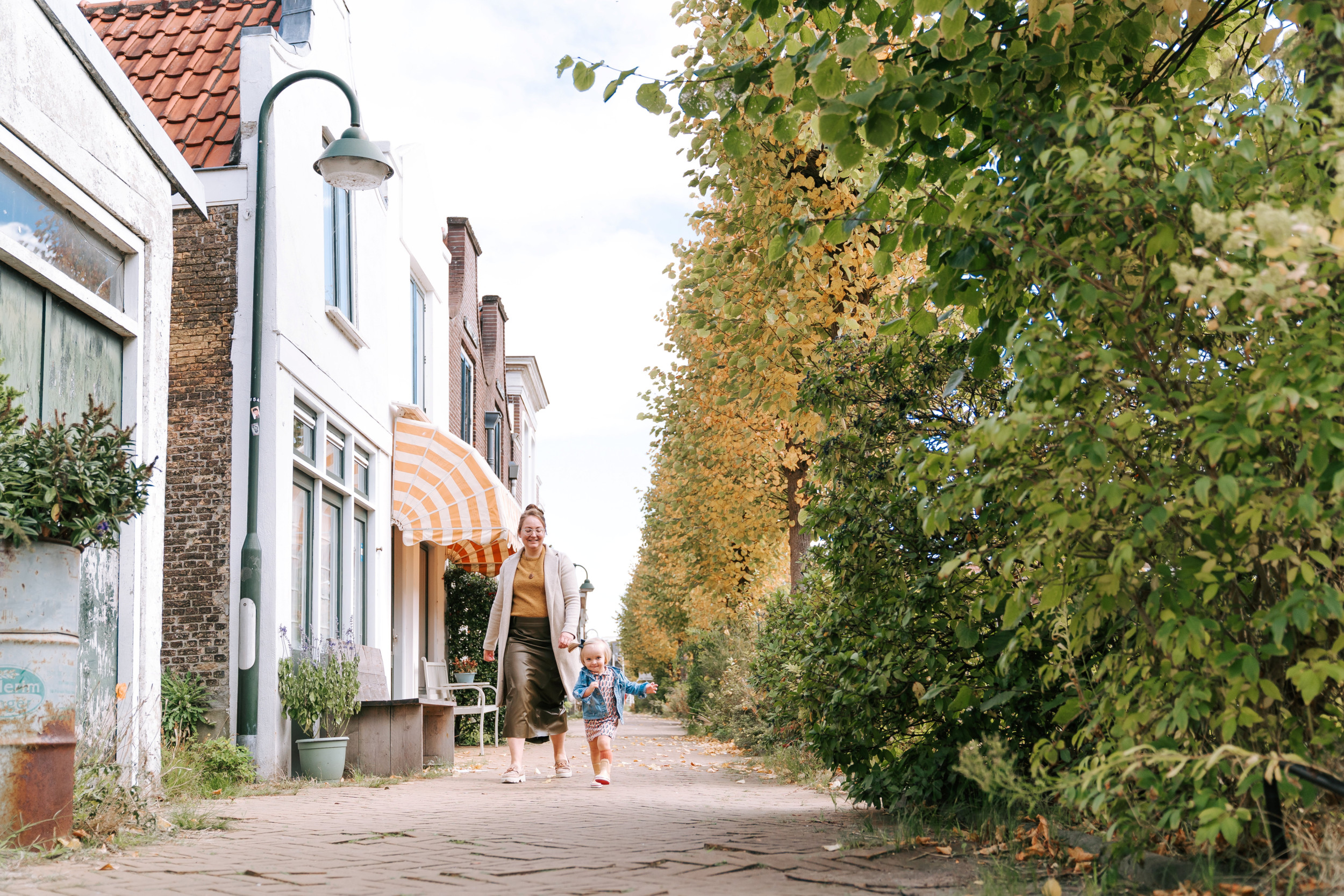 Jonge vrouw, wandelend in een oud straatje, met een meisje naast zich.