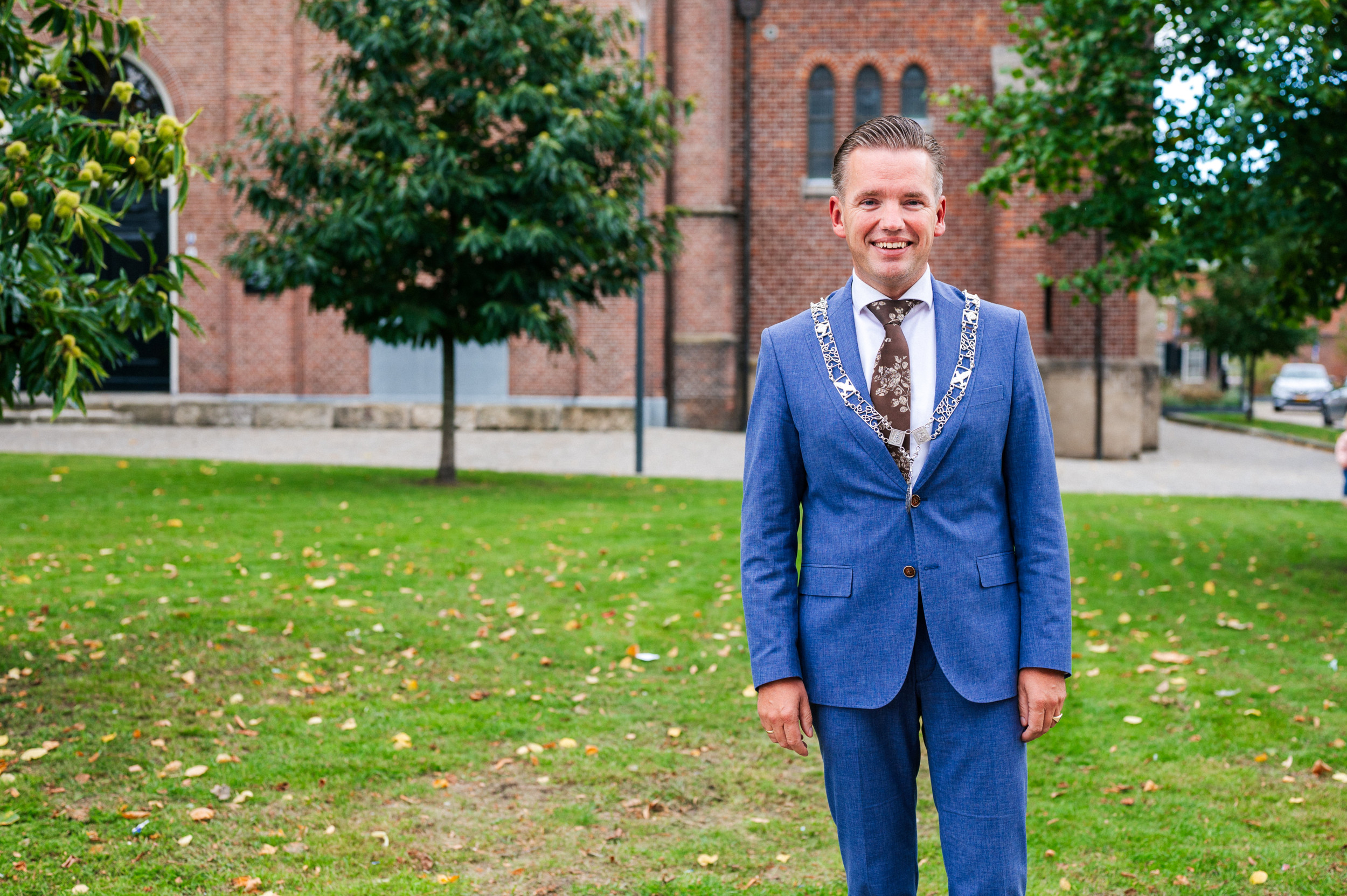 Burgemeester Jurgen van Houdt, met ambsketen om, voor de eeuwenoude Schildkerk in het centrum van Rijssen.