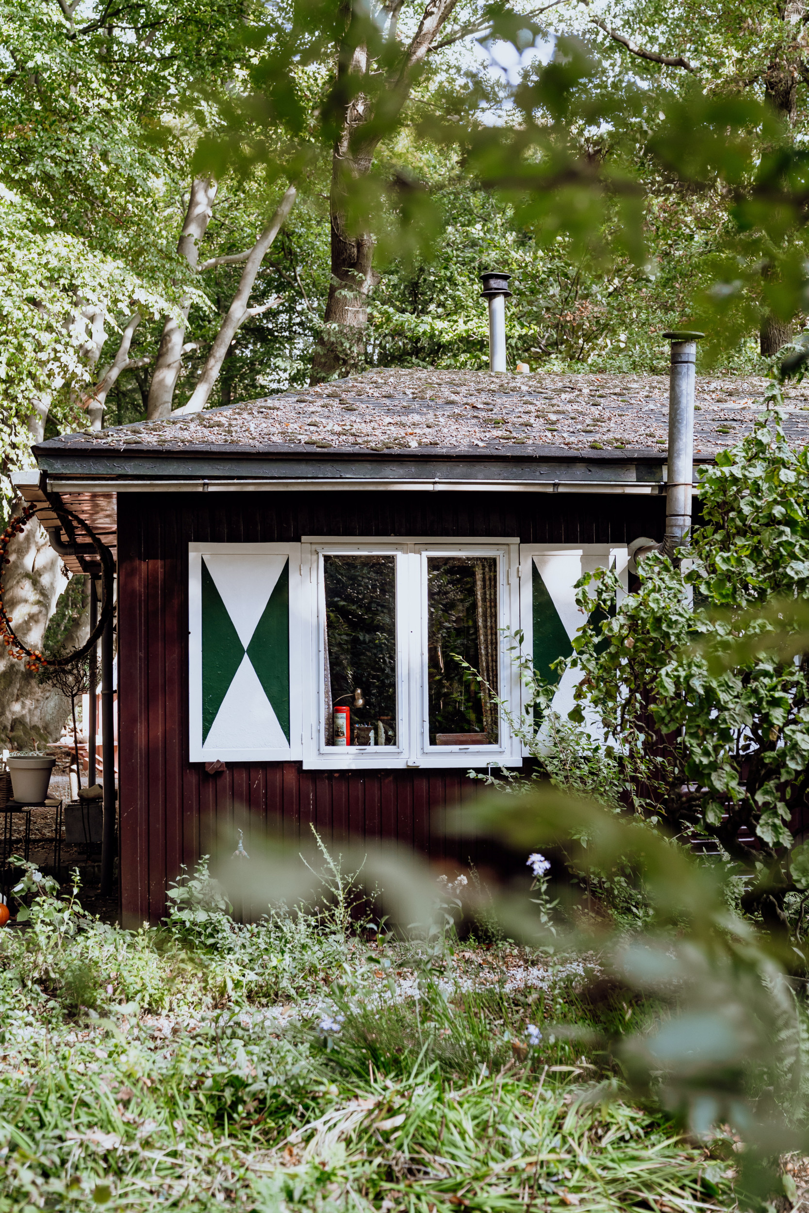 Het boshuisje is gemaakt van donker hout en heeft ramen die voorzien zijn van grote luiken.