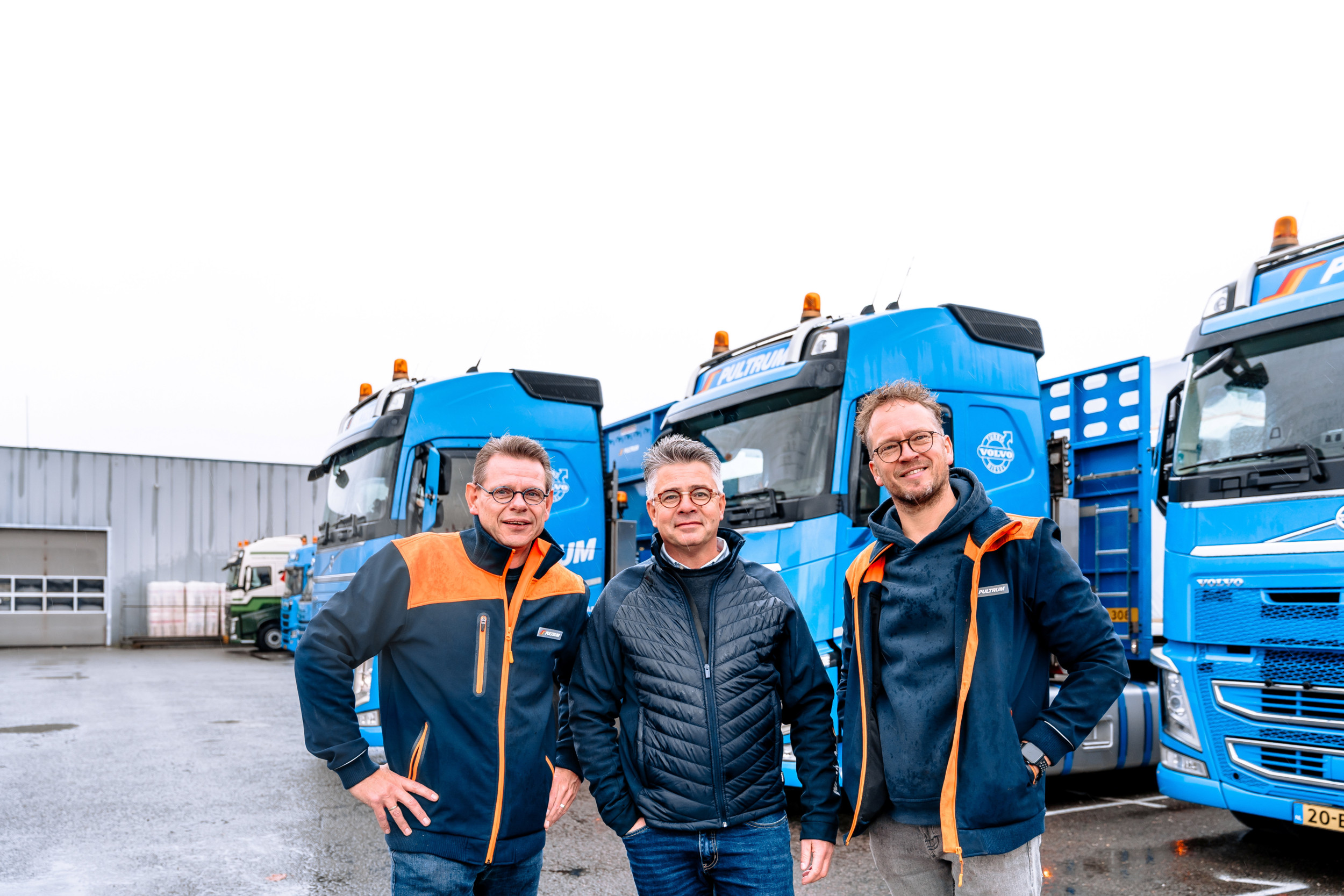 Marcel, Eelco en Gert-Jan (v.l.n.r.) staan voor de blauwe vrachtwagens van Pultrum, waar ze als hobby op rijden.