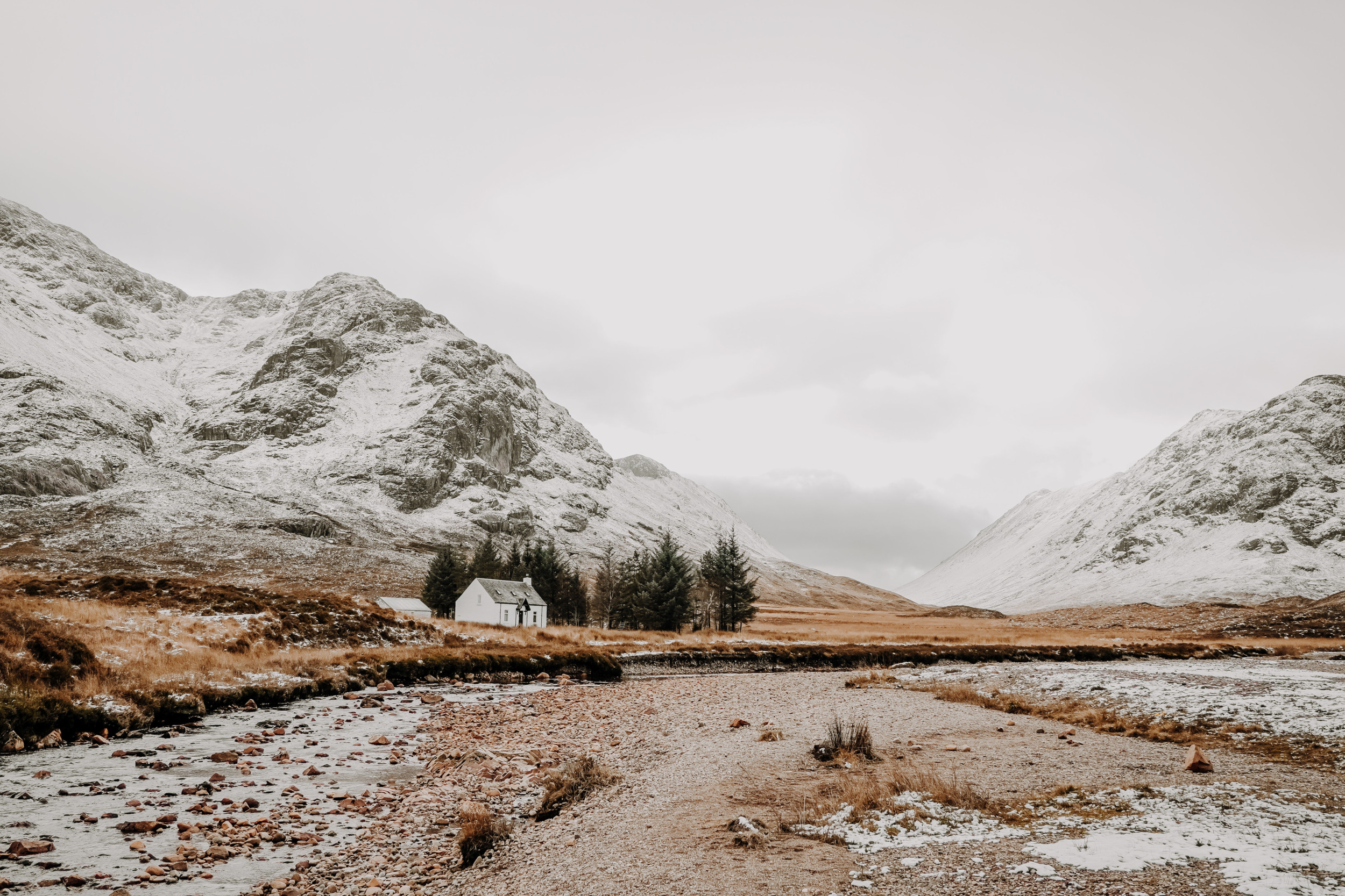 Heuvellandschap met sneeuw en een wit huis.