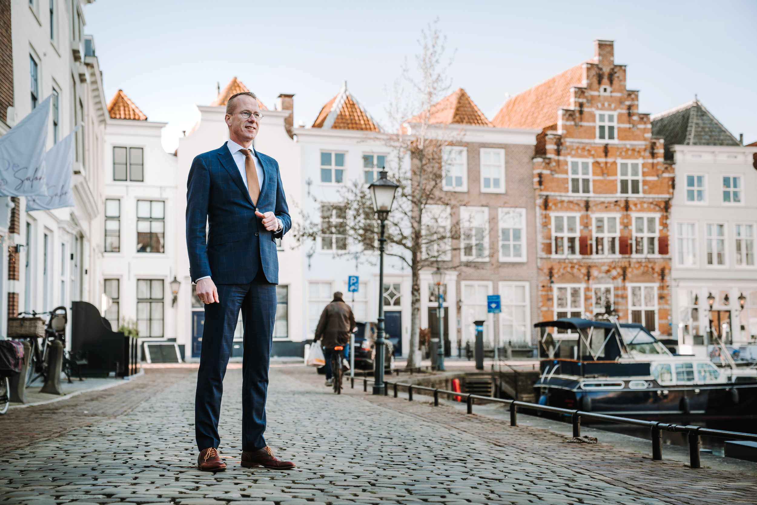 Man in blauw pak voor historische panden in de haven van Goes.