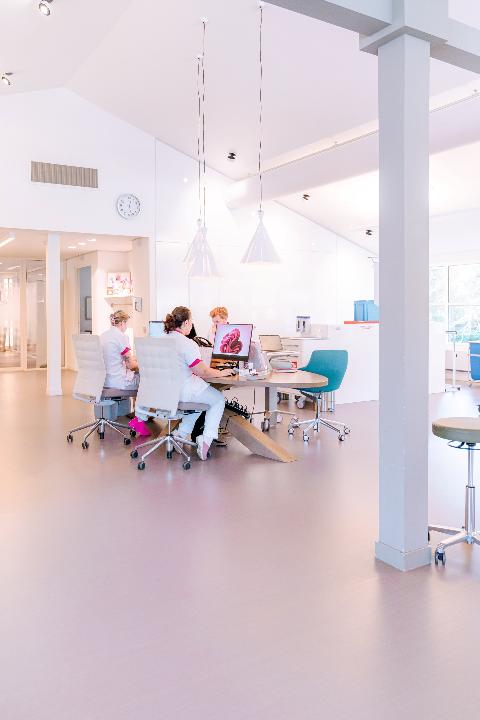 Verpleegkundigen in witte kleding achter een bureau met computers.