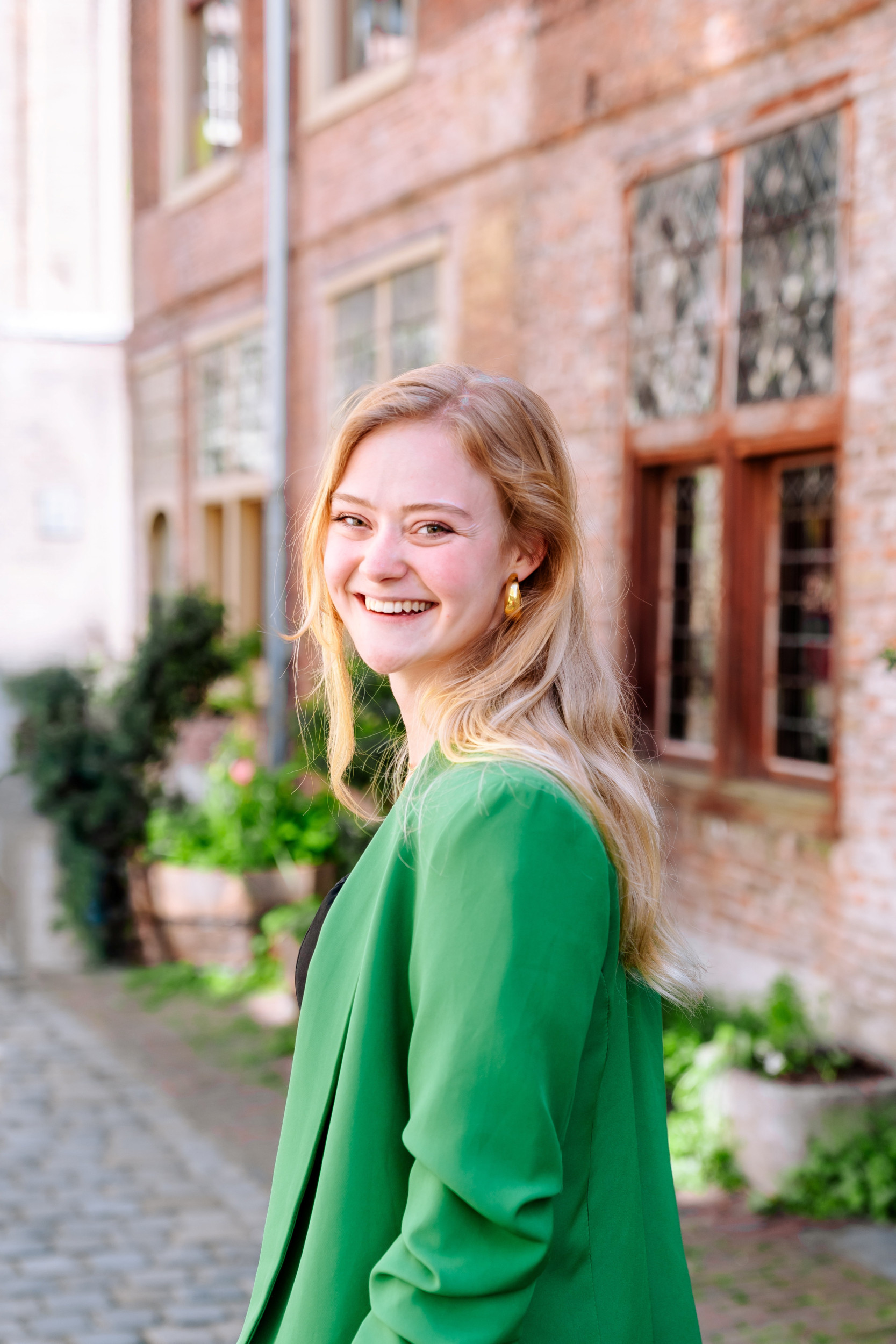 Jonge vrouw in donkere jurk en groen jasje.