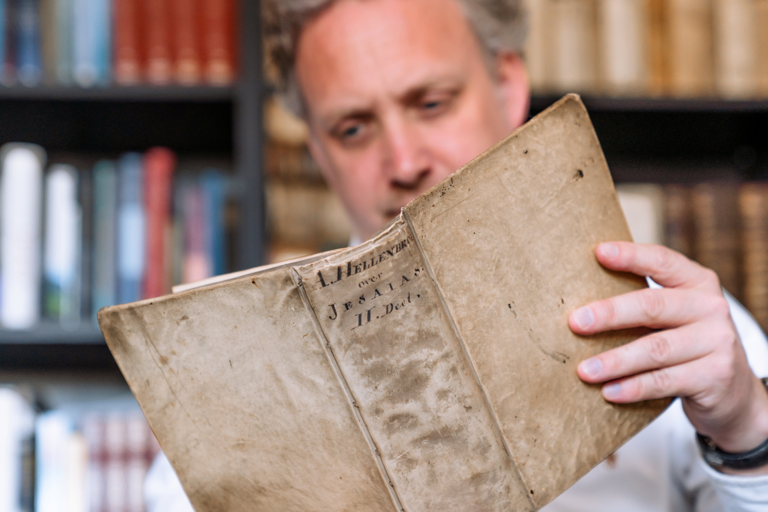 Man leest uit een oud boek met omslag van perkament.