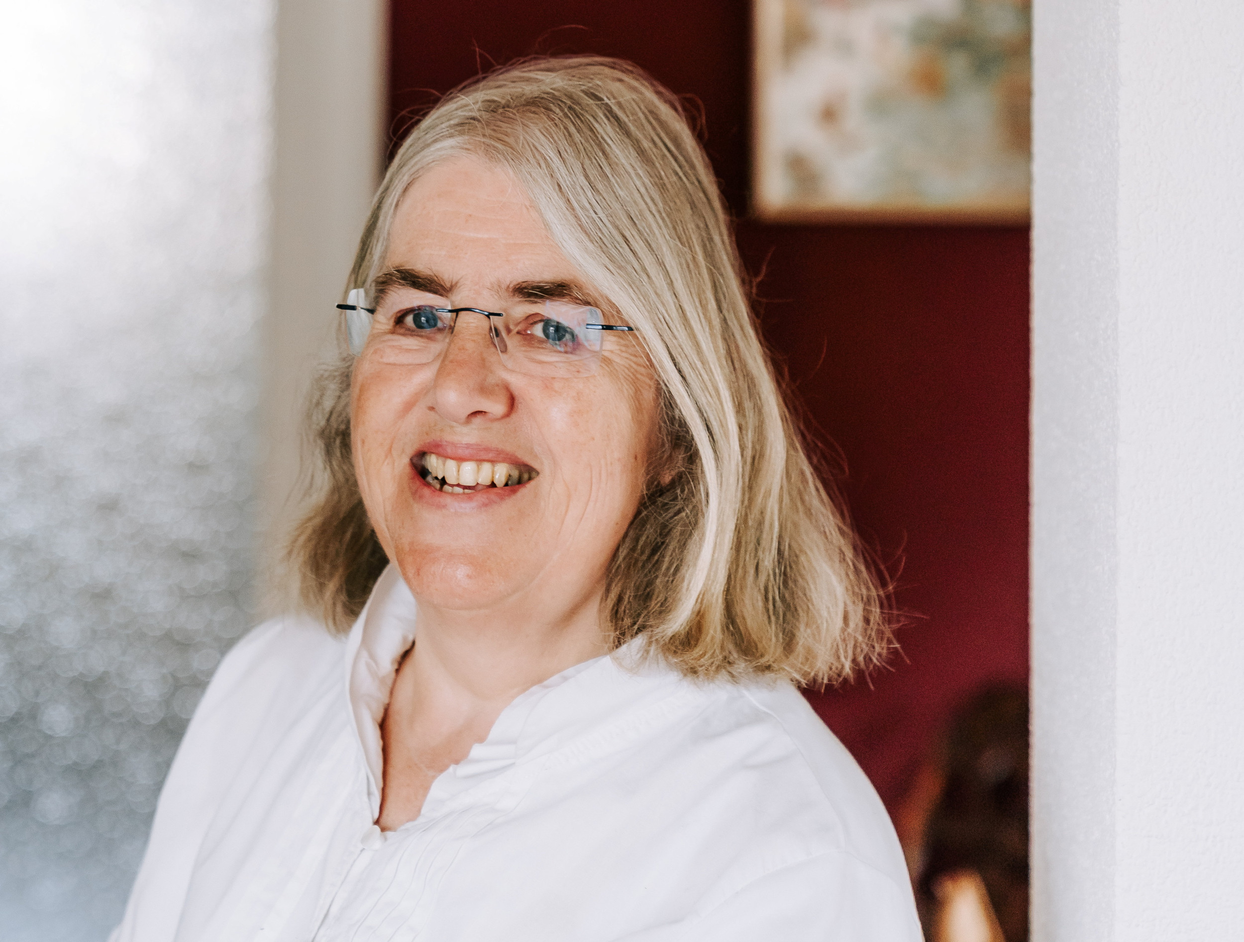 Portret van vrouw met blond haar en witte blouse.