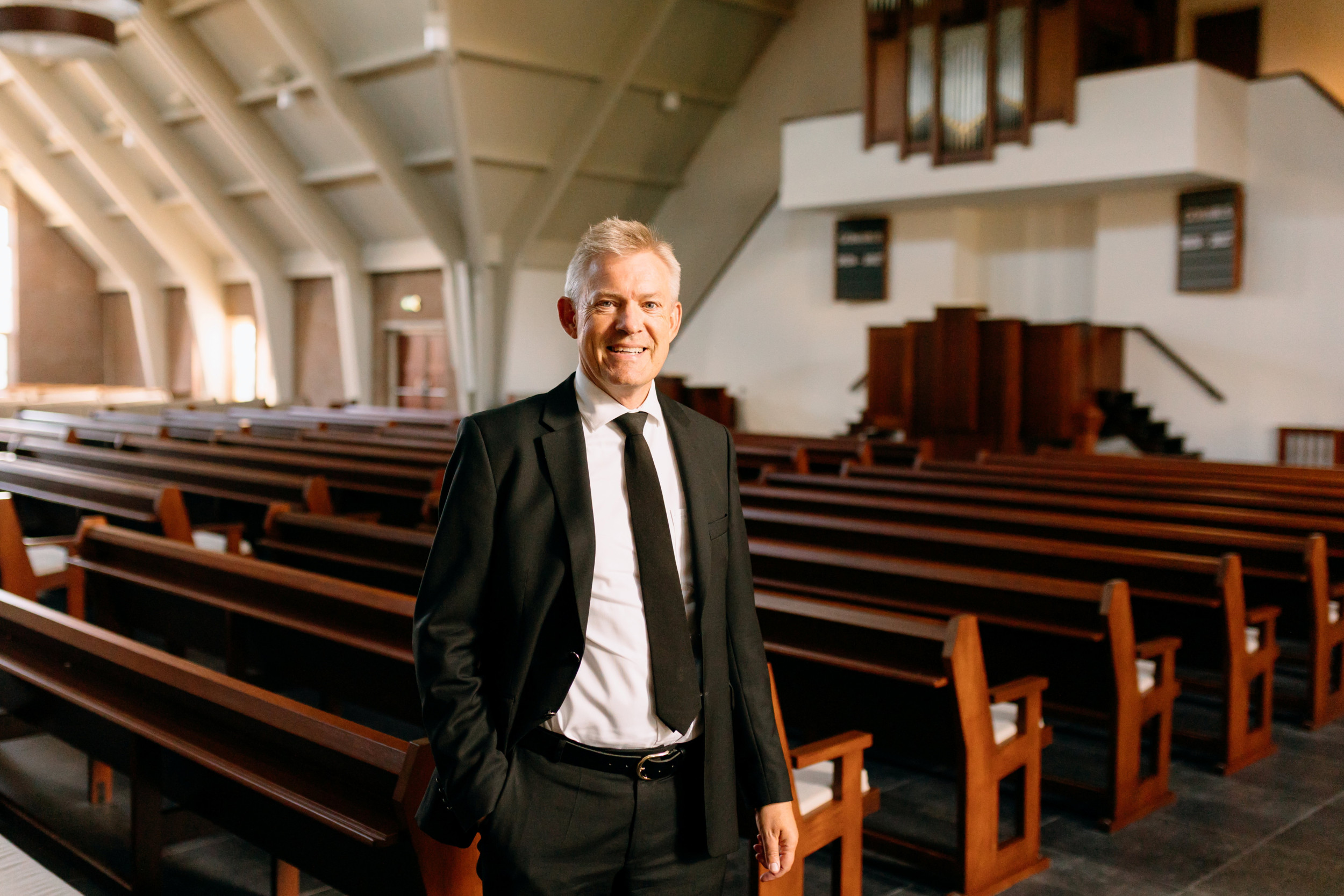 Man van middelbare leeftijd in zwart kostuum in een kerk.